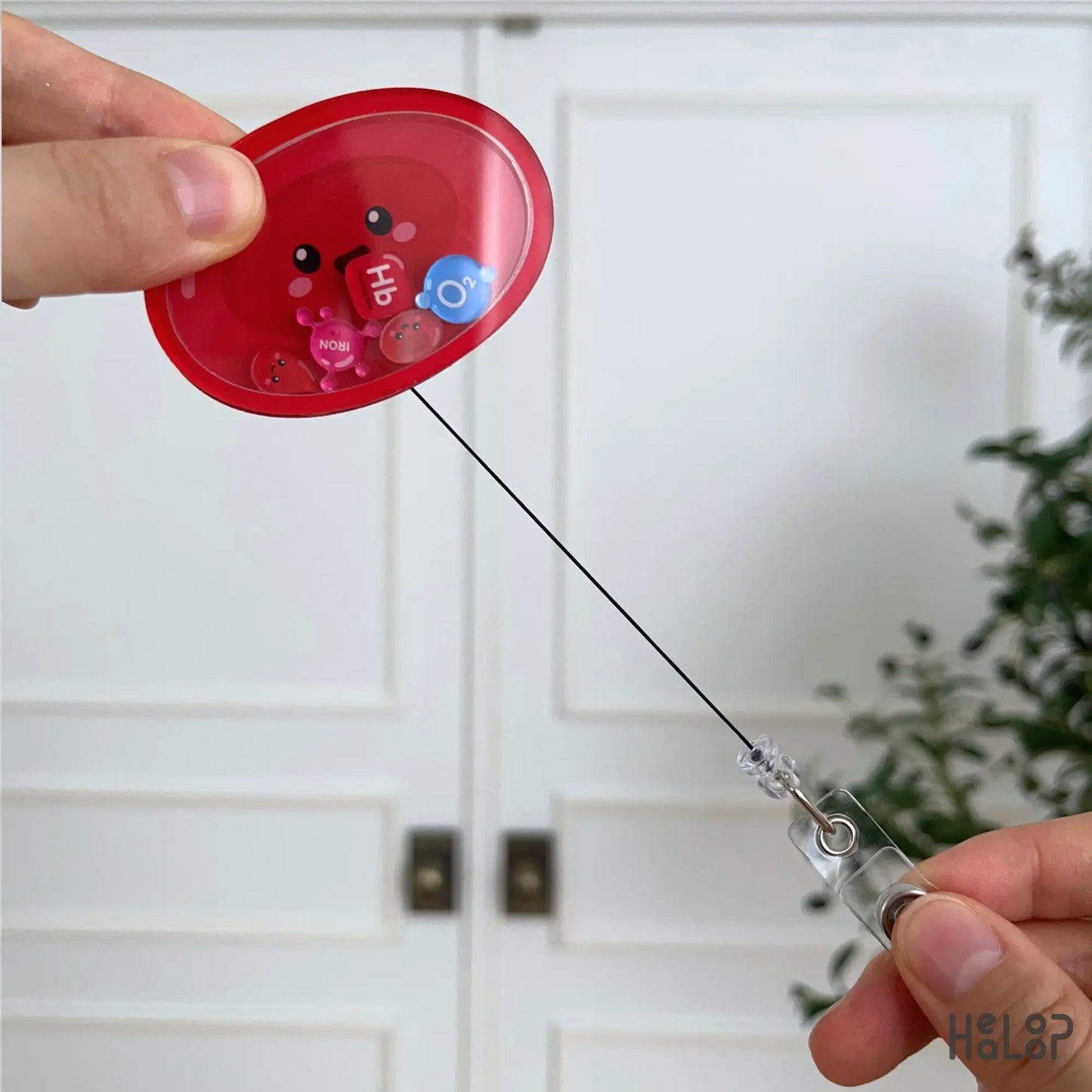 Retractable Red Blood Cell acrylic shaker badge reel featuring hematology-inspired movable charms including Hb, iron, O₂, and red blood cells.