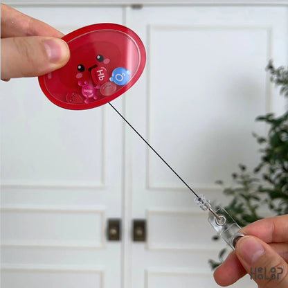 Retractable Red Blood Cell acrylic shaker badge reel featuring hematology-inspired movable charms including Hb, iron, O₂, and red blood cells.