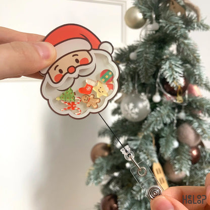 Front close-up of Healoop Santa Shaker Badge Reel featuring Christmas tree, candy cane, and gingerbread charms