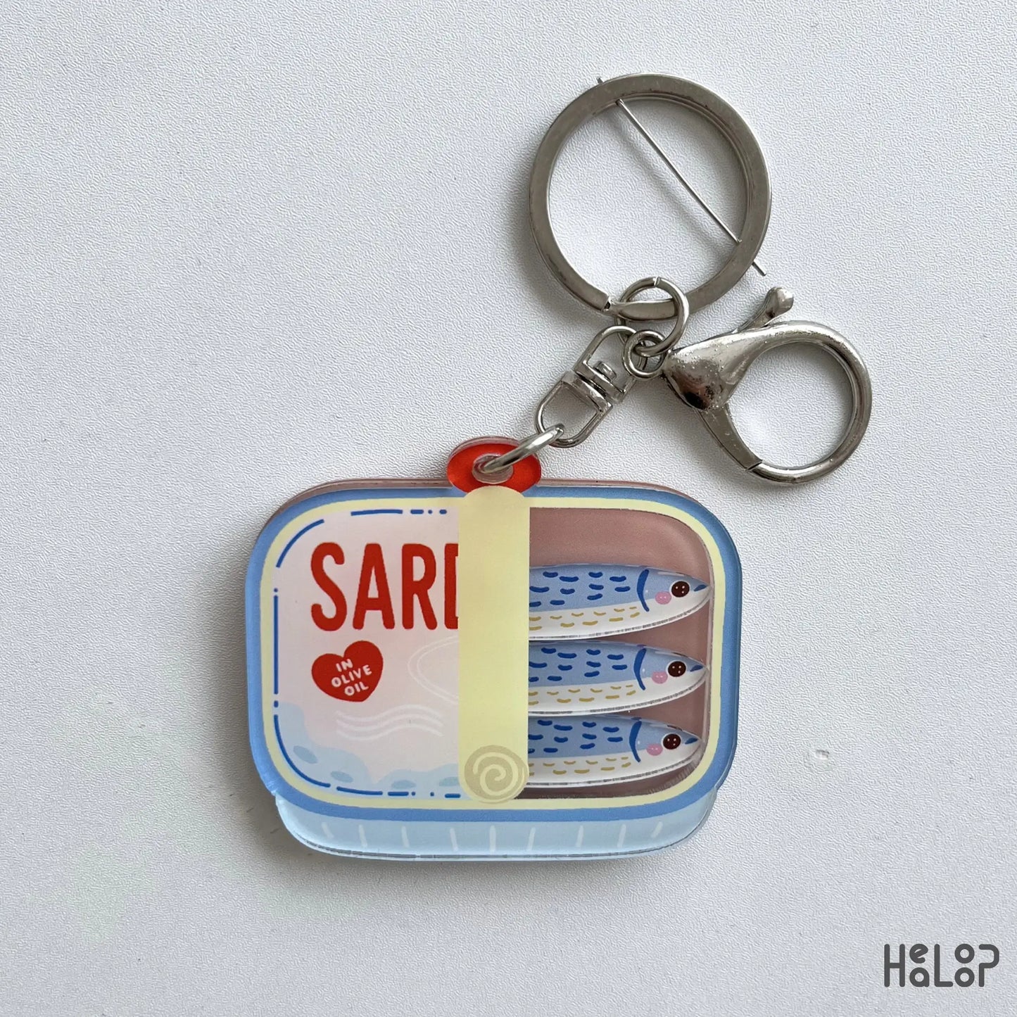 Sardine Shaker Keychain featuring three moving fish charms inside a colorful tinned fish design with silver keychain hardware.
