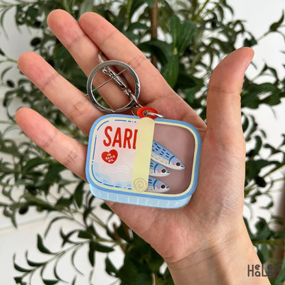 Sardine shaker keychain with moving fish charms displayed in hand, a cute tinned fish accessory by Healoop.