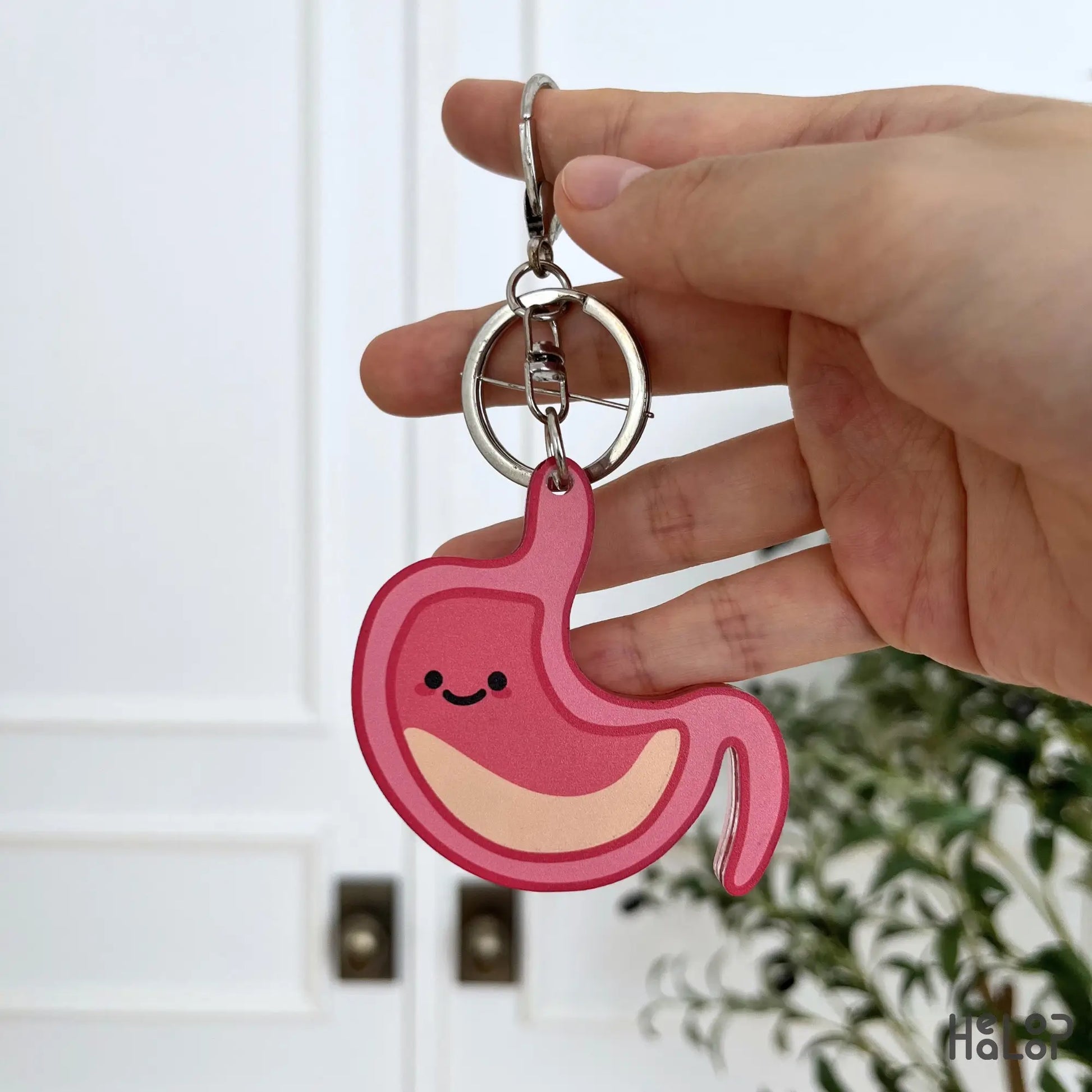 Back view of a cute pink anatomical stomach keychain with a smiling face.