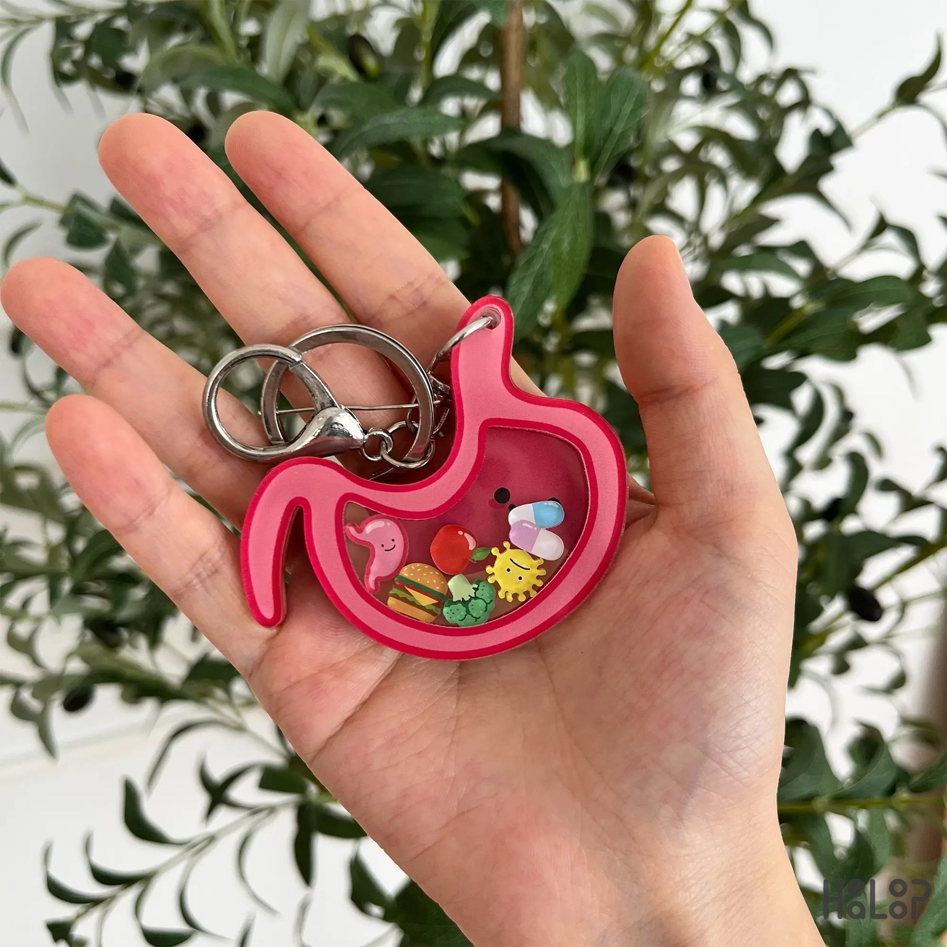 Stomach shaker keychain with colorful moving charms held in hand.