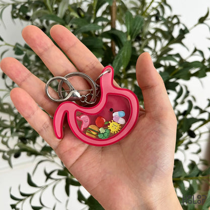 Stomach shaker keychain with colorful moving charms held in hand.