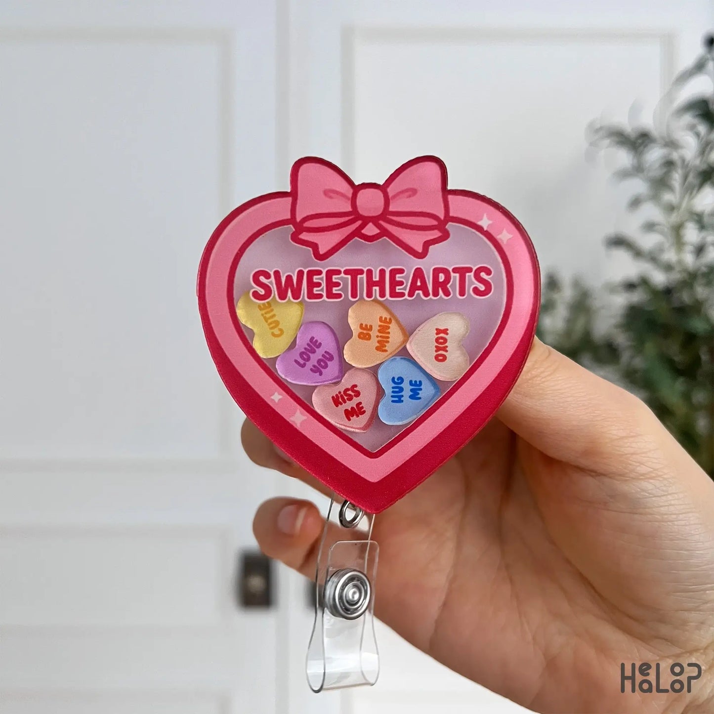 Detailed front view of Sweethearts badge reel featuring pastel candy heart charms