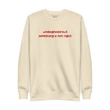 Bone-colored sweatshirt with 'undiagnosed but something is not right' embroidered in red, displayed flat for a detailed view.