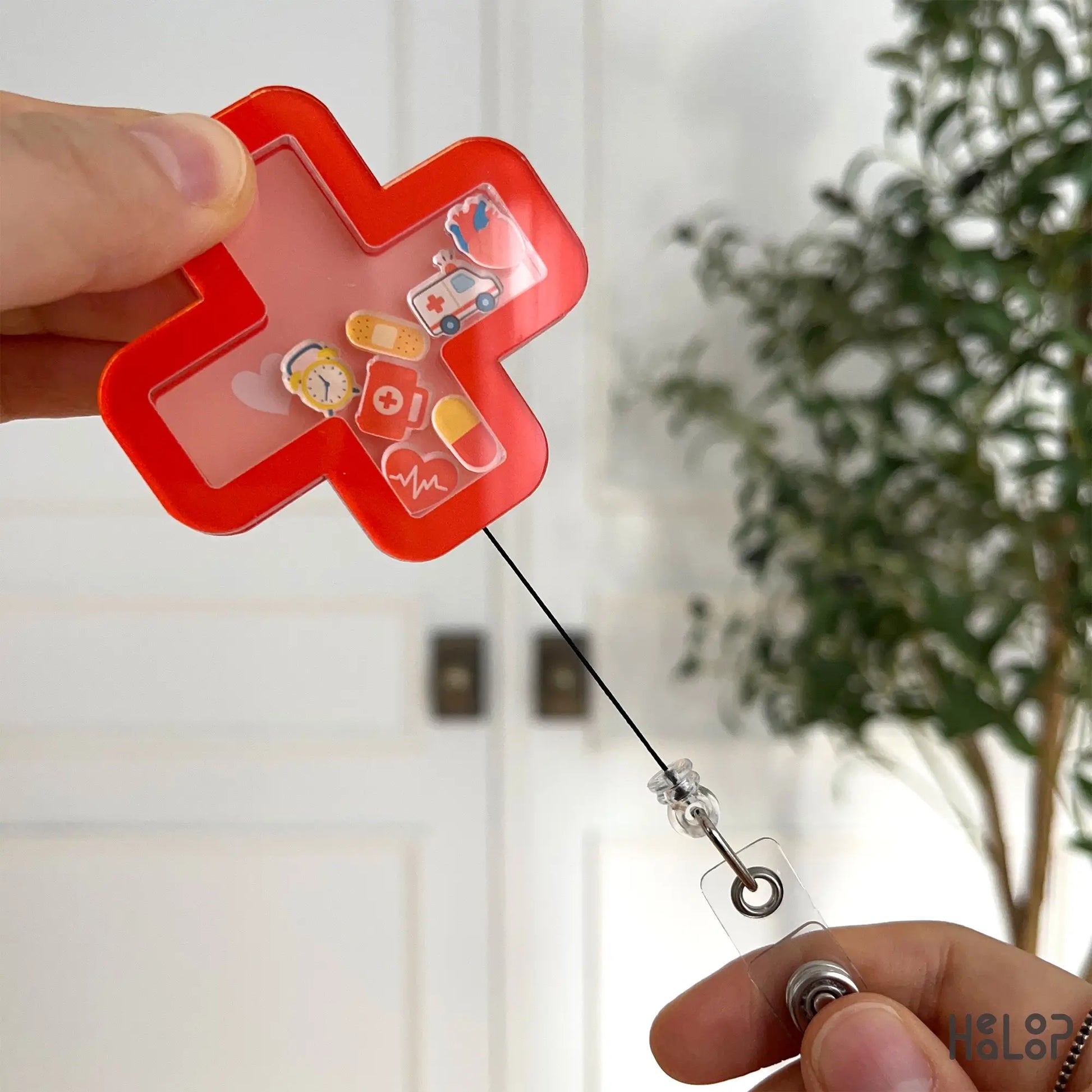 Red cross urgent care badge reel extended to show retractable cord and clear clip