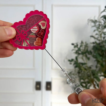 Retractable heart chocolate shaker badge reel being pulled to show cord extension